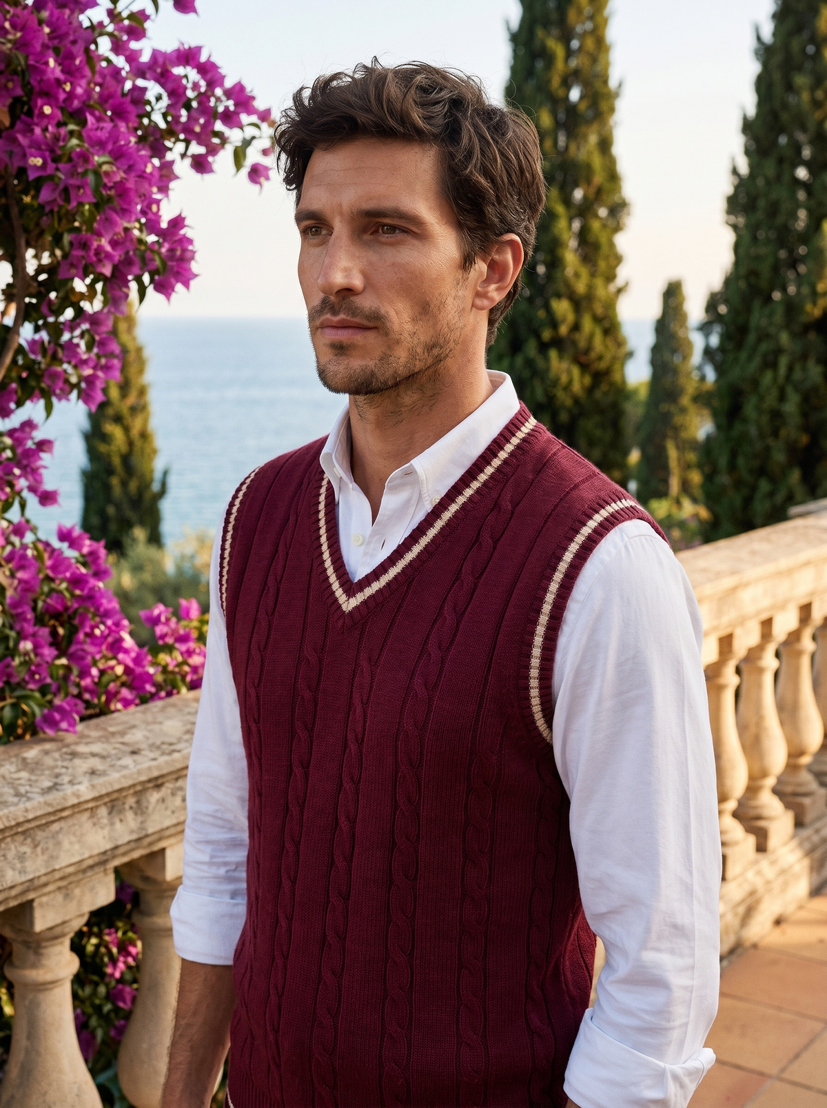 Man wearing a burgundy contrast-trim sweater vest over a shirt on a balcony overlooking Lake Como, old money style — Belvoirne