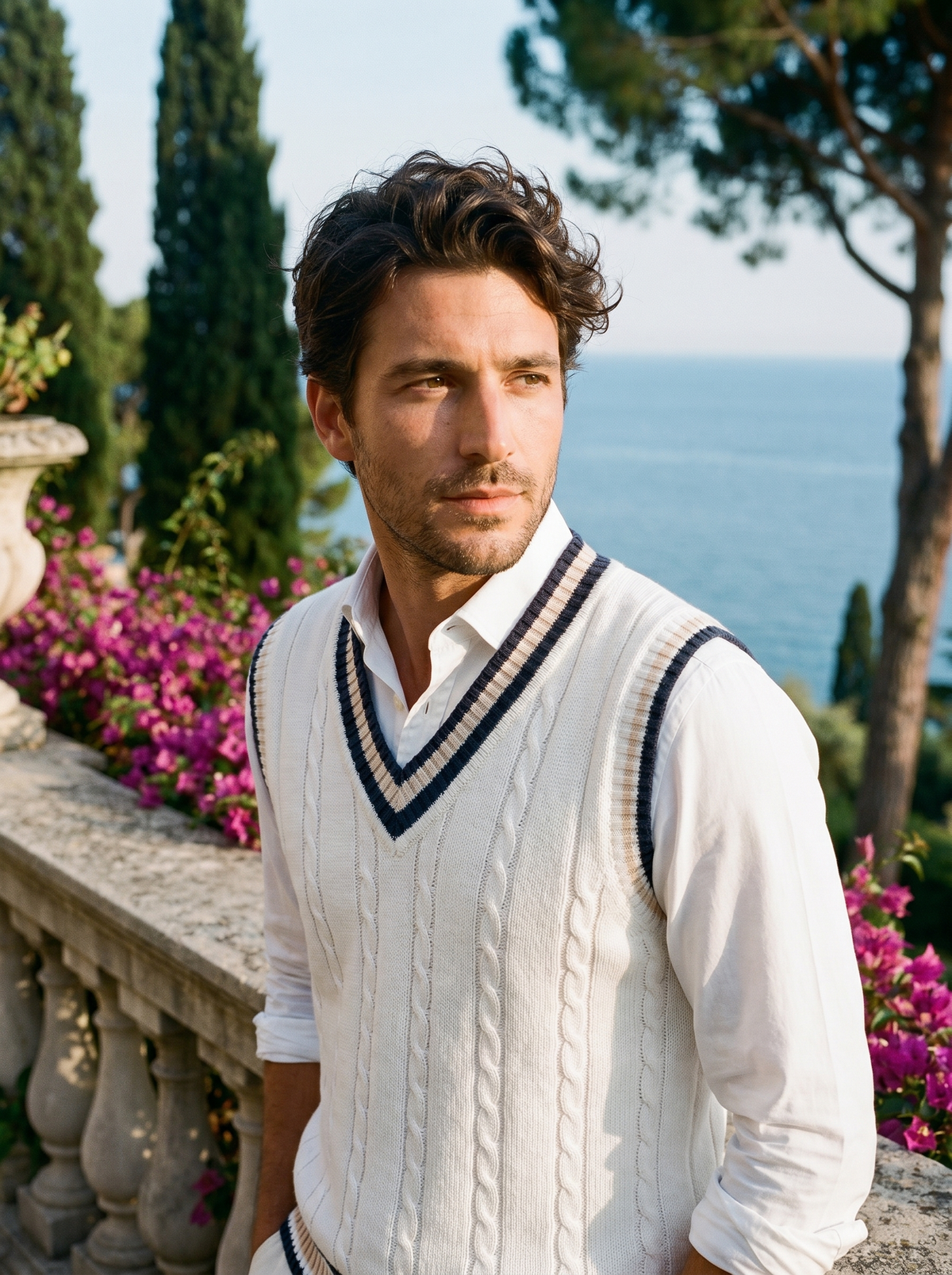 Man wearing a white contrast-trim sweater vest over a shirt on a balcony overlooking Lake Como, old money style — Belvoirne