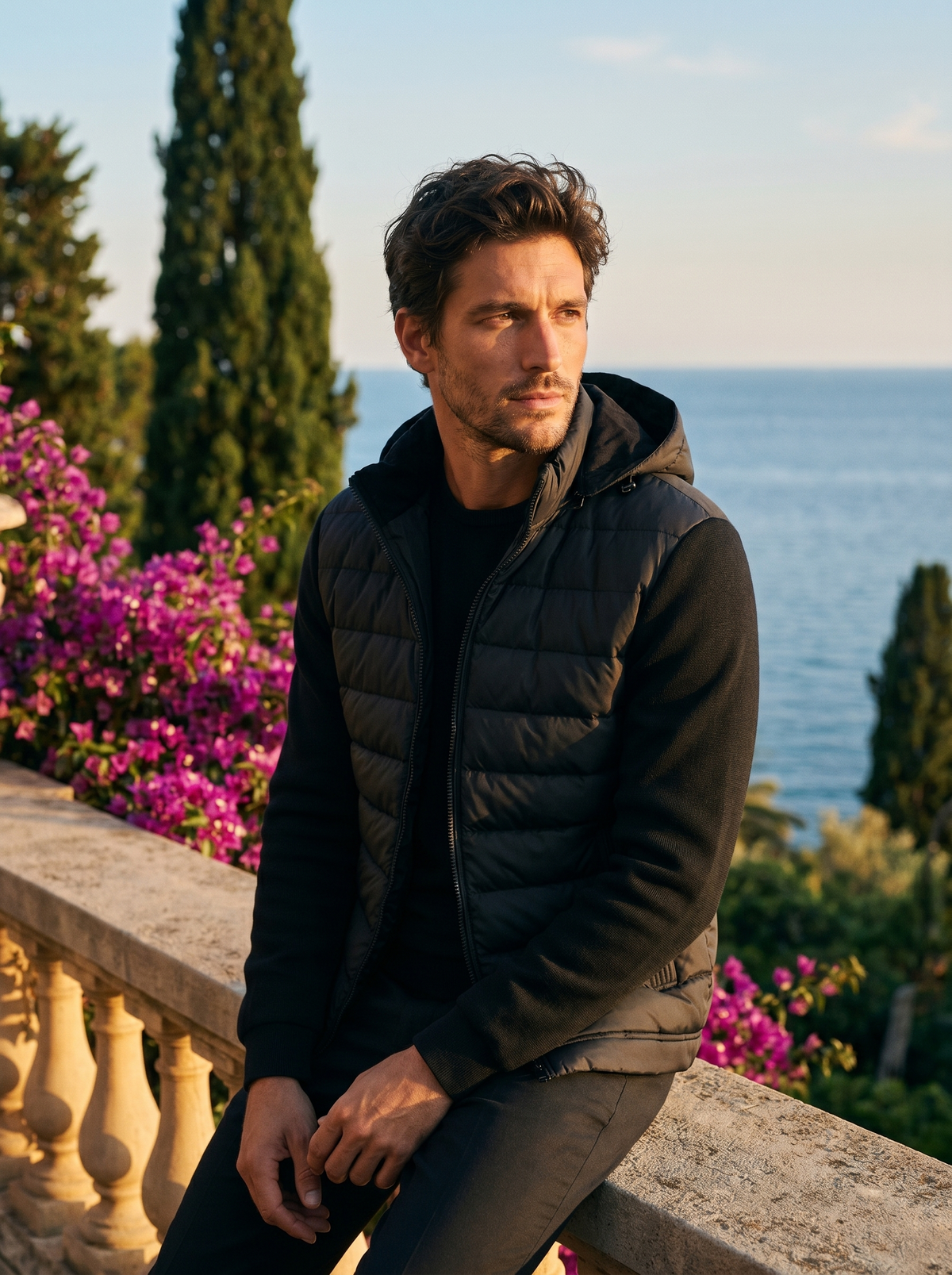 Man wearing a black hooded puffer jacket on a balcony overlooking Lake Como, old money style — Belvoirne