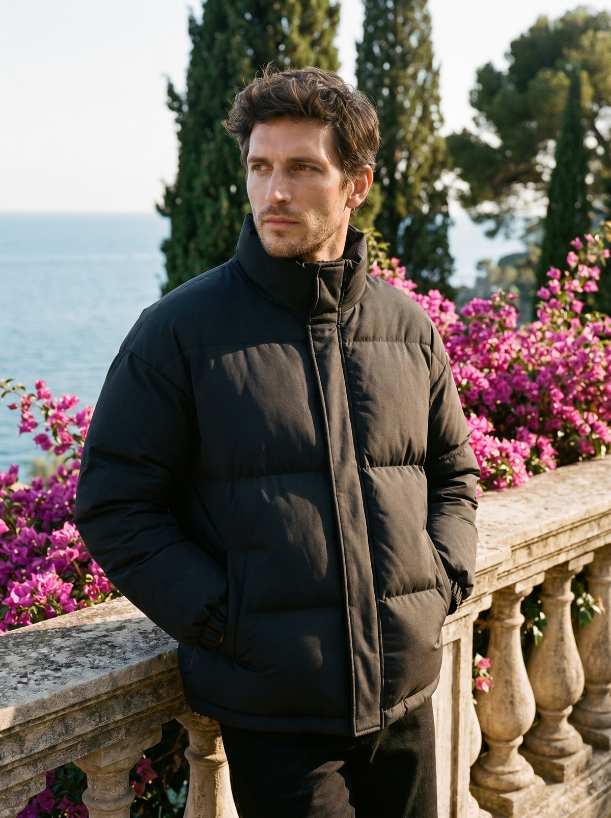 Man wearing a black puffer jacket on a balcony overlooking Lake Como, old money style — Belvoirne