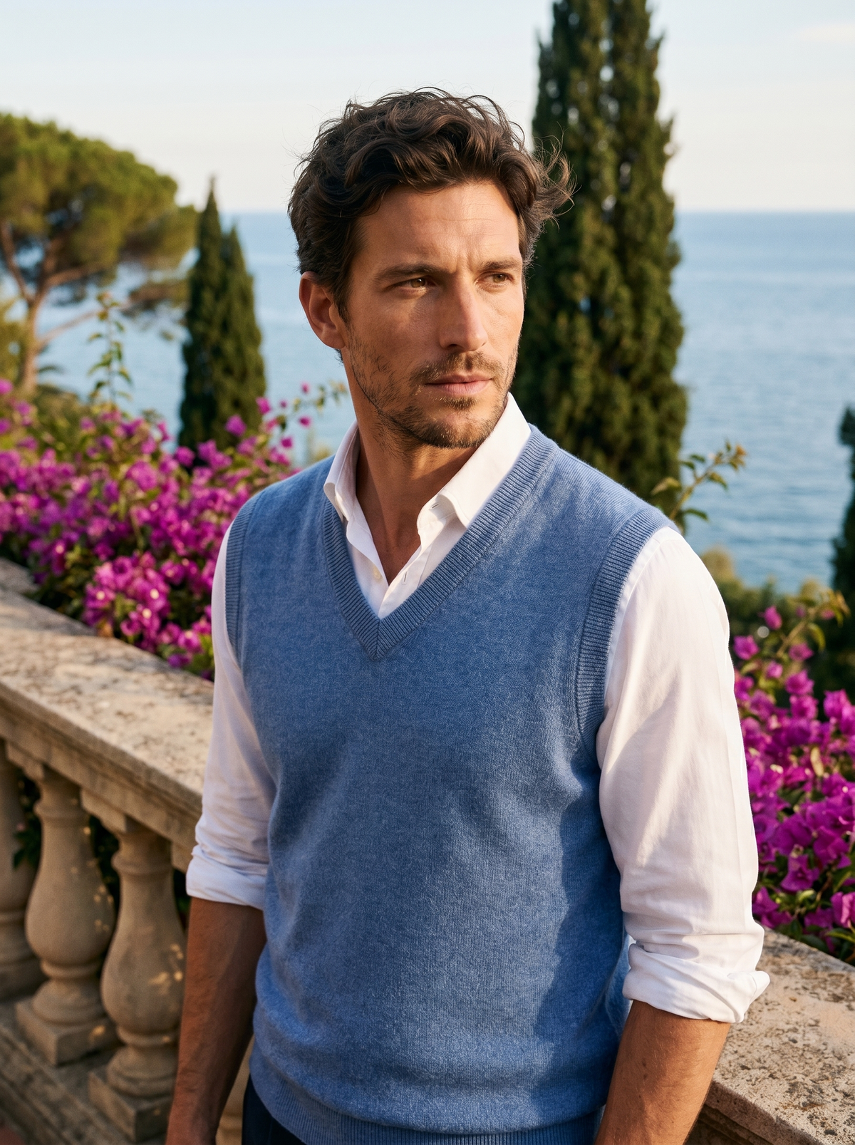 Man wearing a blue wool sweater vest over a shirt on a balcony overlooking Lake Como, old money style — Belvoirne