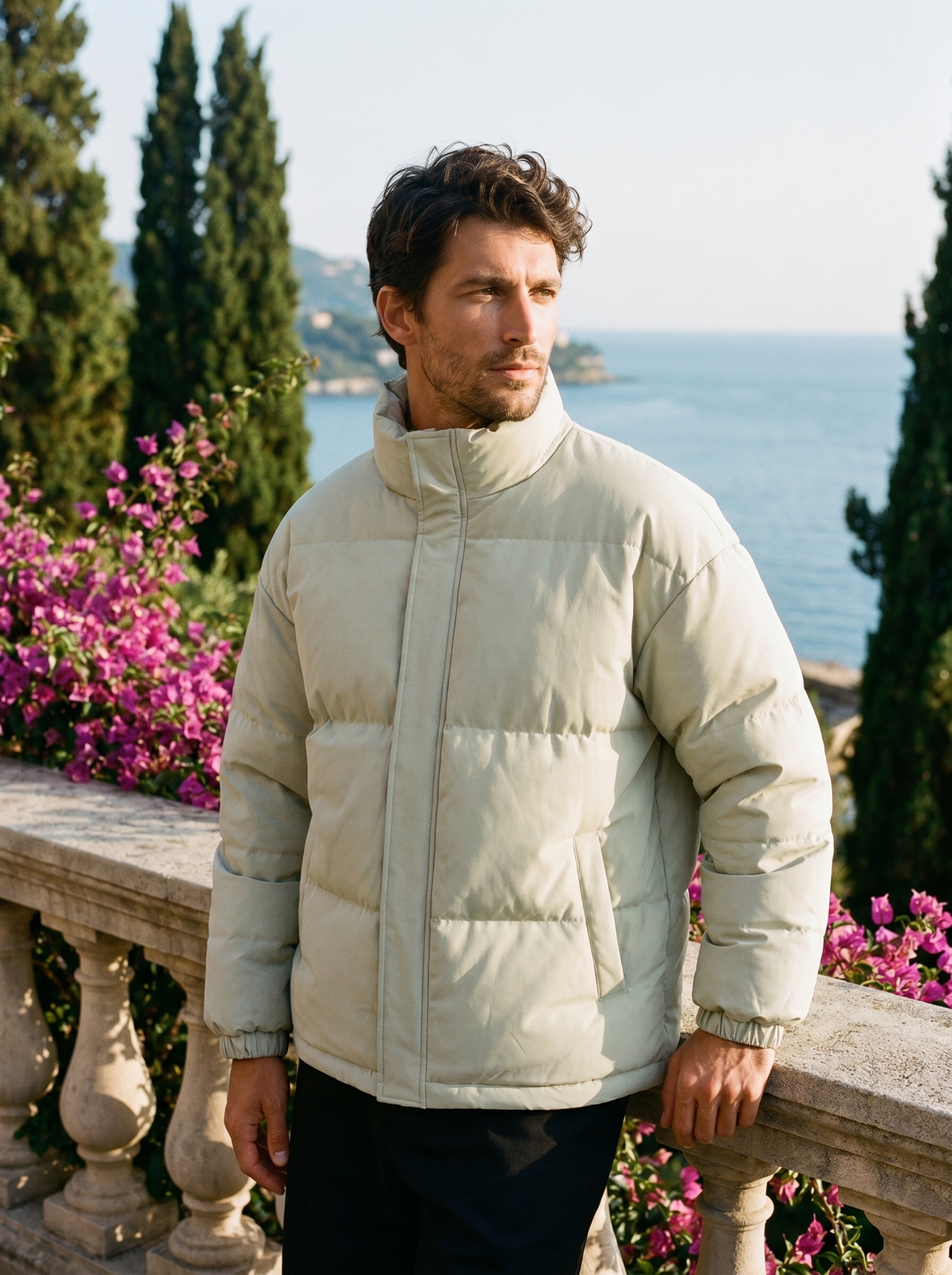 Man wearing an olive puffer jacket on a balcony overlooking Lake Como, old money style — Belvoirne